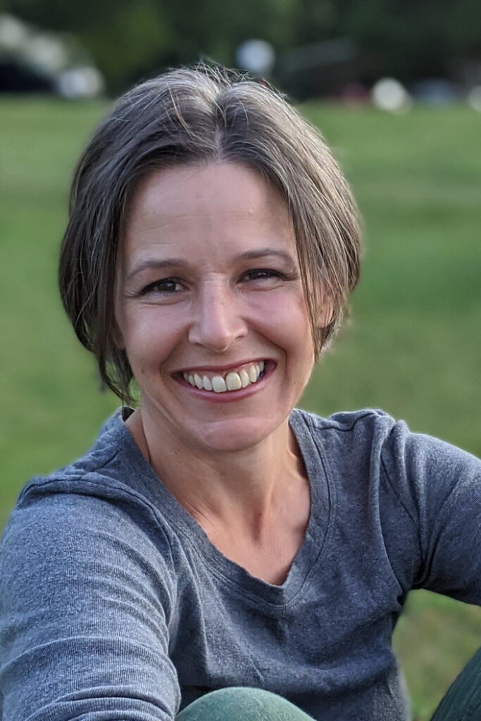 woman sitting with arms wrapped around knees smiling at the camera