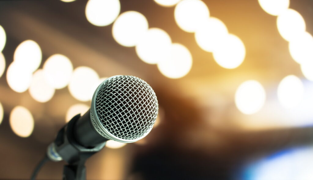 Microphone on abstract blurred of speech in seminar room or speaking conference hall light Event concert bokeh background