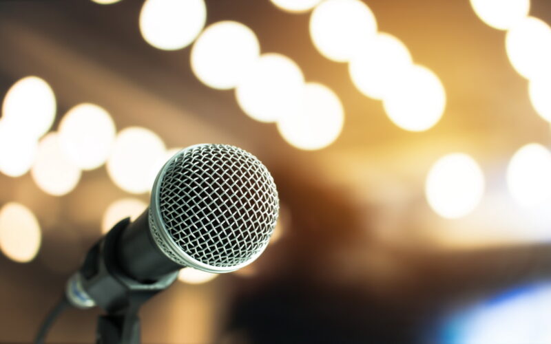 Microphone on abstract blurred of speech in seminar room or speaking conference hall light Event concert bokeh background