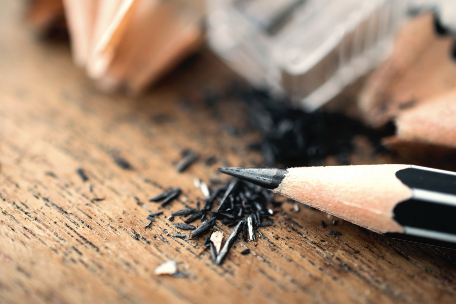 sharpened pencil with sharpening shavings on wooden table