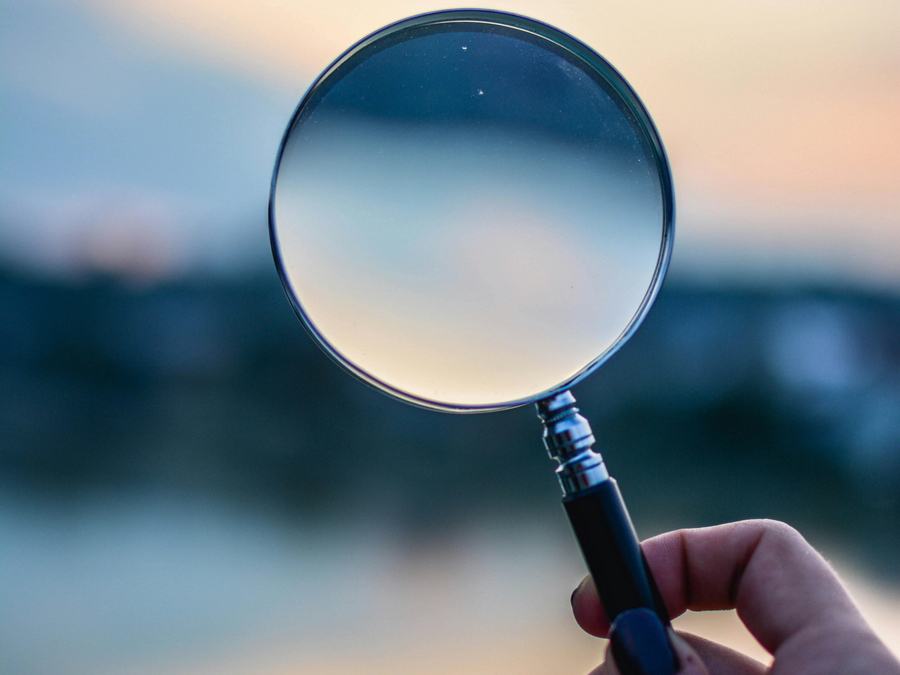 magnifying glass held up to a blurry horizon line at twilight