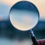 magnifying glass held up to a blurry horizon line at twilight