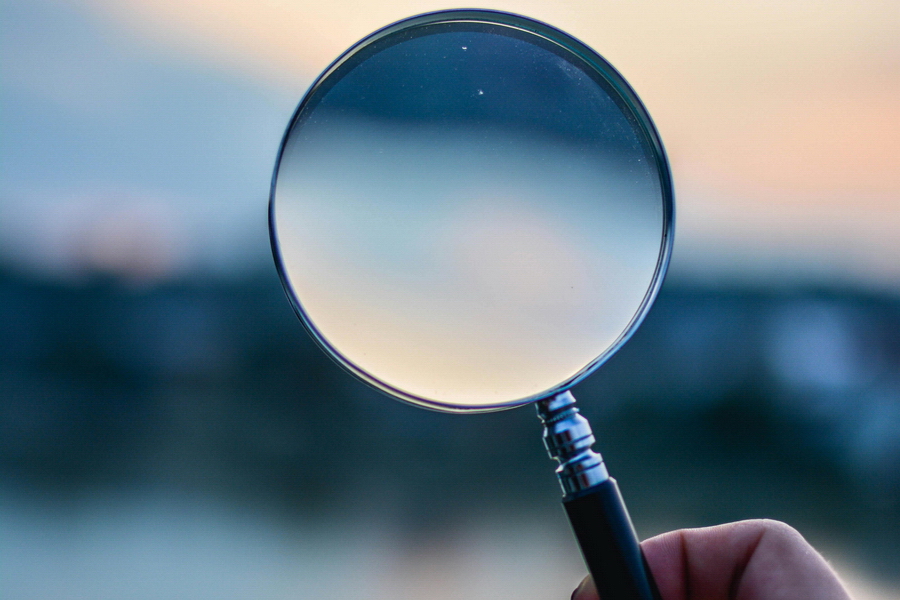 magnifying glass held up to a blurry horizon line at twilight